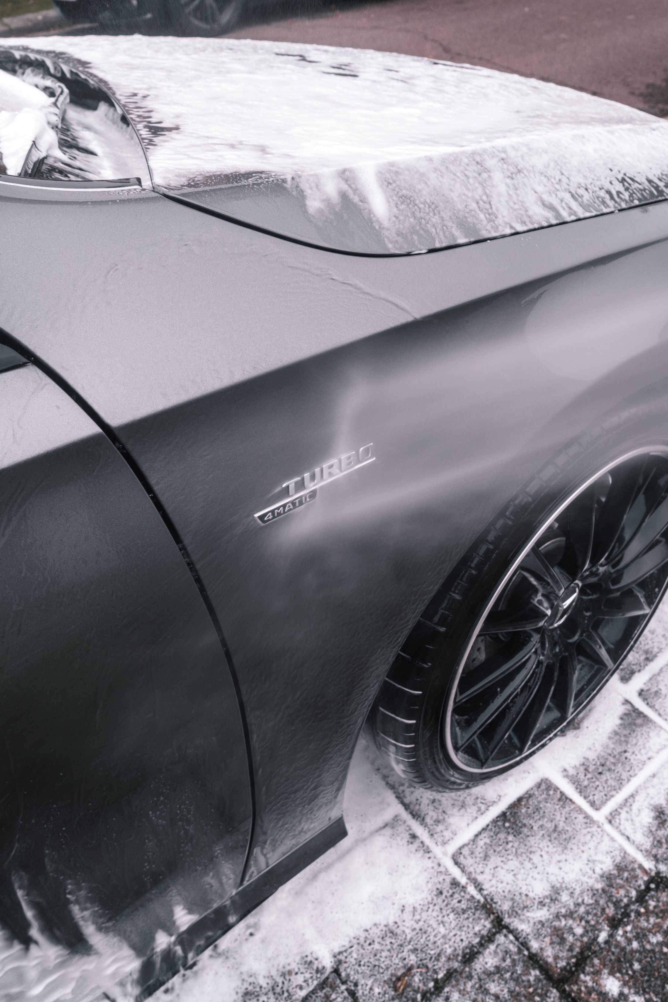 A dark car covered with wash foam
